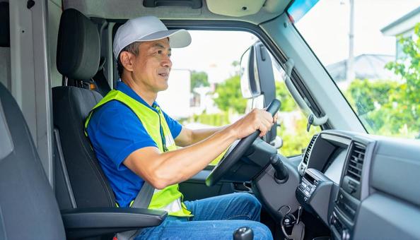 トラックを運転する男性ドライバーの横顔 トラックを運転する男性ドライバーの横顔の写真