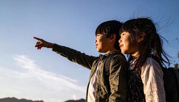 夕焼けの空を見つめる日本人の少年少女 夕焼けの空を見つめる日本人の少年少女の写真
