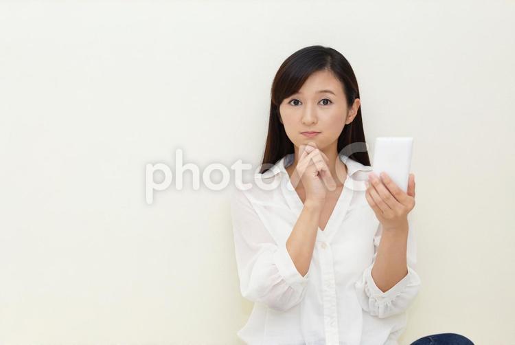 スマートフォンを持って考える女性 女性,スマホ,スマートフォンの写真素材