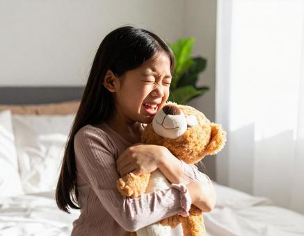 泣きながらぬいぐるみを抱きしめる女の子 泣きながらぬいぐるみを抱きしめる女の子の写真