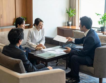 応接室でお客様に資料を説明する上司と部下の写真