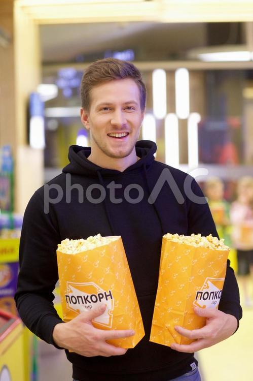 映画館のロビーでポップコーンを持っている男性15 映画館,売店,男性の写真素材