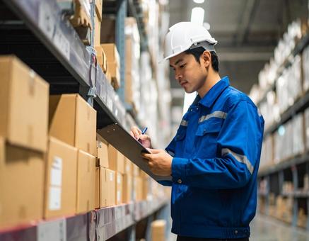 倉庫で在庫をチェックする男性作業員の写真
