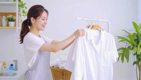 雨の日に洗濯物を部屋干しする女性 雨の日に洗濯物を部屋干しする女性の写真