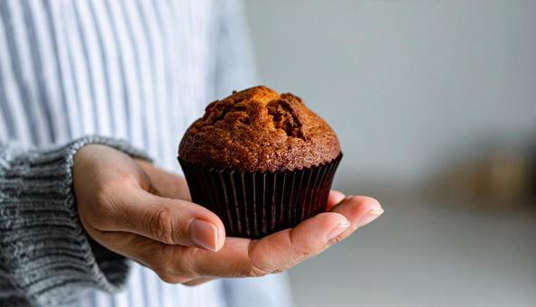 手に持ったスイートポテトのマフィン 手に持ったスイートポテトのマフィンの写真
