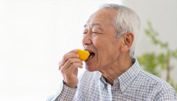酸っぱいレモンを食べるシニア男性 酸っぱいレモンを食べるシニア男性の写真