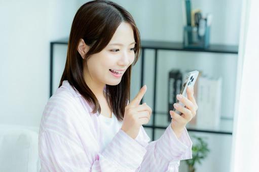 部屋でスマホを操作する若い女性 部屋でスマホを操作する若い女性 スマホ,笑顔,女性の写真素材