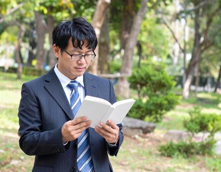 屋外で読書しているサラリーマン 屋外で読書しているサラリーマンの写真