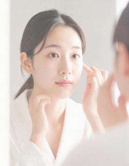 鏡の前でメイクする女性 鏡の前でメイクする女性の写真