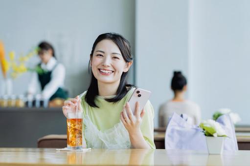 カフェでスマホを見る若い女性 女性,カフェ,笑顔の写真素材