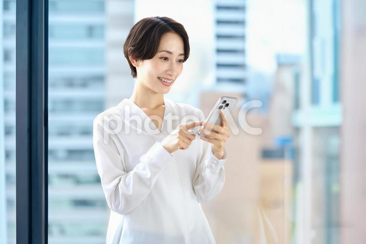 オフィスでスマホを使うビジネスウーマン スマホ,ビジネスウーマン,女性の写真素材