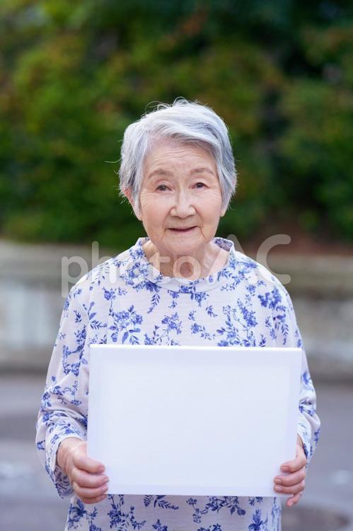 メッセージボードを持ち立つ女性 女性,高齢者,メッセージボードの写真素材