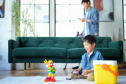 携帯を見て掃除する男性とロボットを操縦する男の子 携帯を見て掃除する男性とロボットを操縦する男の子 親子,男性,男の子の写真素材