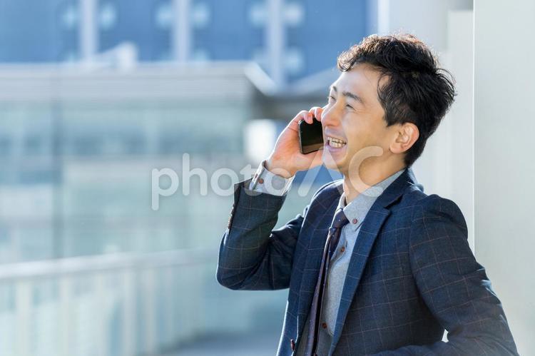 スマホで通話をする笑顔の男性ビジネスマン 男性,ビジネス,ビジネスマンの写真素材