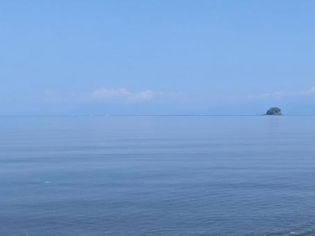 穏やかな海の水面と遠くに写る小島 穏やかな海の水面と遠くに写る小島の写真
