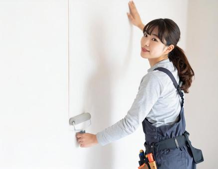 内装施工で壁紙を貼る女性の大工さん 内装施工で壁紙を貼る女性の大工さんの写真
