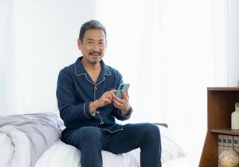寝室でスマホを見るミドルの男性 寝室でスマホを見るミドルの男性 男性,スマホ,ミドルの写真素材