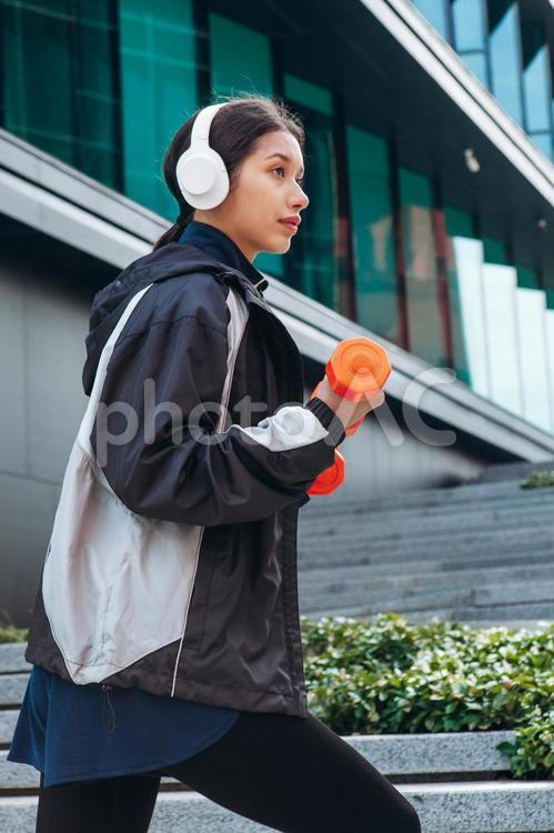 階段をダンベルを持って歩く女性の横顔 女性,ヘッドフォン,筋トレの写真素材