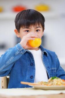 真顔でオレンジジュースを飲む男の子 男の子,ジュース,飲むの写真素材