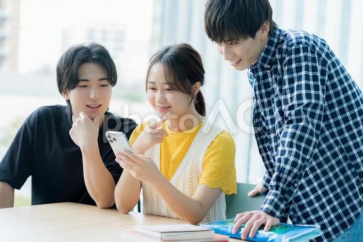 スマホを見ながら話す学生たち 大学生,スマホ,教室の写真素材