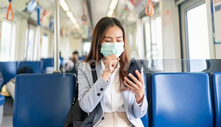 電車の中で咳をするマスク女性 マスク,鼻水,せきの写真素材