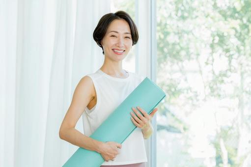 リビングでヨガをする女性 リビングでヨガをする女性 ミドル,持つ,ヨガマットの写真素材