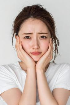 頬に手を当てる20代日本人女性 頬に手を当てる20代日本人女性の写真