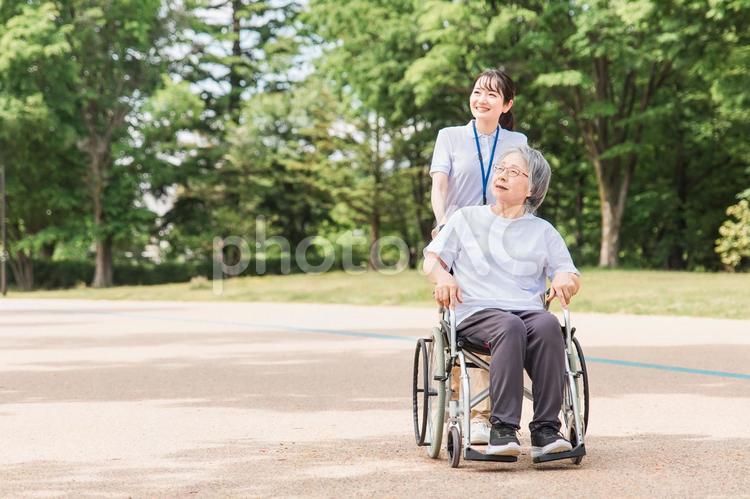 公園を散歩する介護士と車椅子の高齢者女性 ヘルパー,介護,外出介助の写真素材