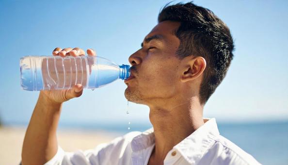 ペットボトルの水を飲む男性 ペットボトルの水を飲む男性の写真