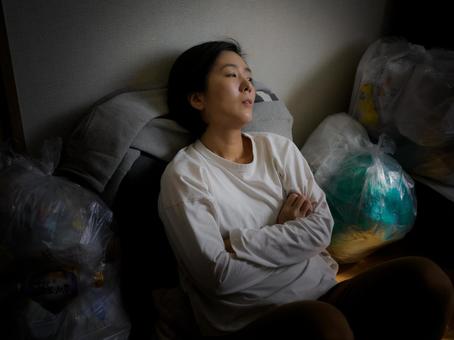 34：ゴミに囲まれている女性 ゴミ部屋,ゴミ屋敷,汚部屋の写真素材