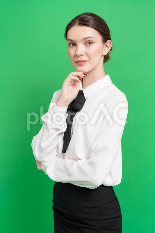 顎に手を当てポーズする女性（緑背景） 女性,立つ,ポーズの写真素材