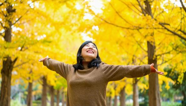紅葉の中で深呼吸する秋服の日本人女性 紅葉の中で深呼吸する秋服の日本人女性の写真