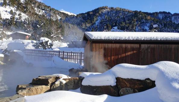 雪の降り積もる岩場の露天風呂の写真