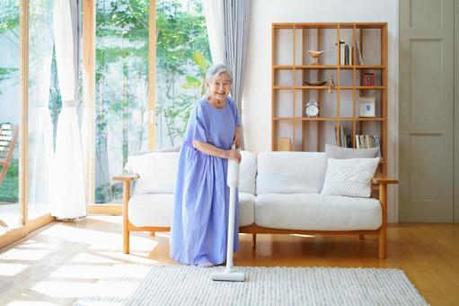 笑顔で掃除機で掃除をしている高齢女性 女性,掃除,掃除機の写真素材