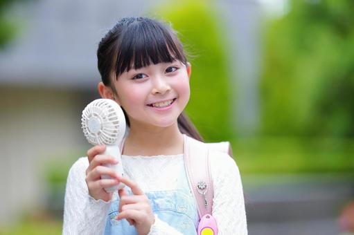 ハンディファンを使うランドセルを背負ったカメラ目線の女の子 子ども,女の子,小学生の写真素材