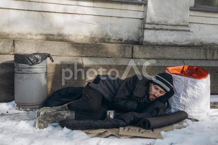 寝転ぶ男性ホームレス 男性,ニット帽,ヒゲの写真素材