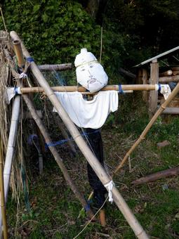 里山で稲掛けを見守る手作りのカカシ 里山で稲掛けを見守る手作りのカカシの写真