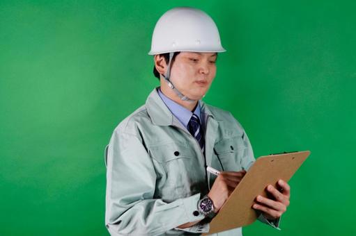 工事現場で書類作業をする男性 作業服,ヘルメット,男性の写真素材