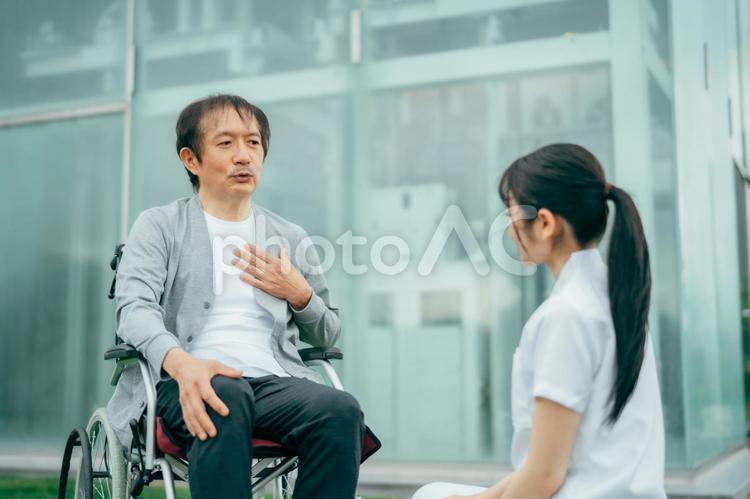 病院の屋上で医療スタッフと話す中高年男性 看護師,介護士,理学療法士の写真素材