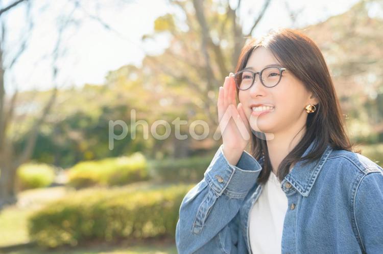 公園で呼びかけるメガネの女性 人物,女性,笑顔の写真素材