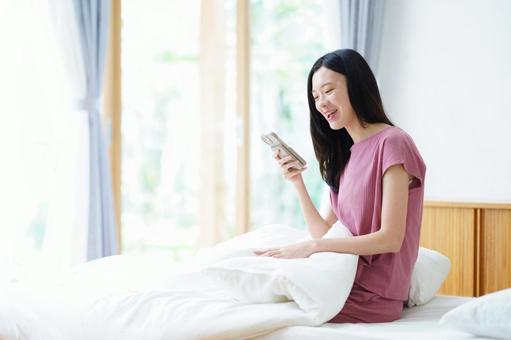 スマホを見て笑うロングヘアの横向き女性 女性,スマートフォン,持つの写真素材