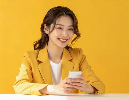 スマホを持つ笑顔の女性 黄色背景 スマホを持つ笑顔の女性 黄色背景の写真