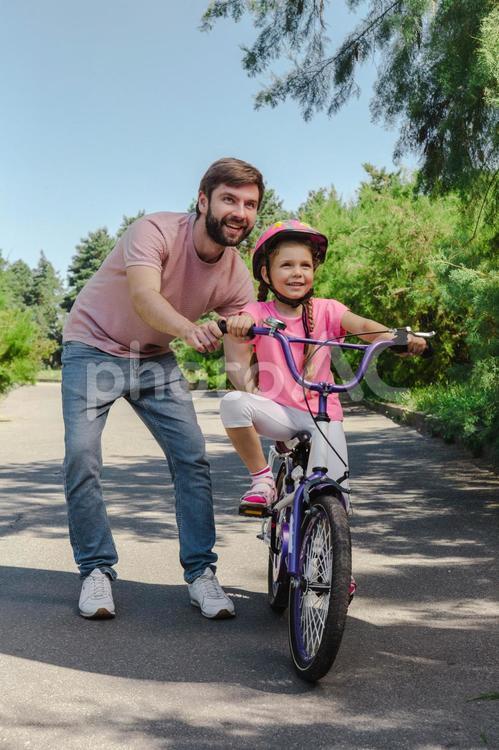自転車の練習をする女の子とサポートするお父さん 自転車,親子,お父さんの写真素材