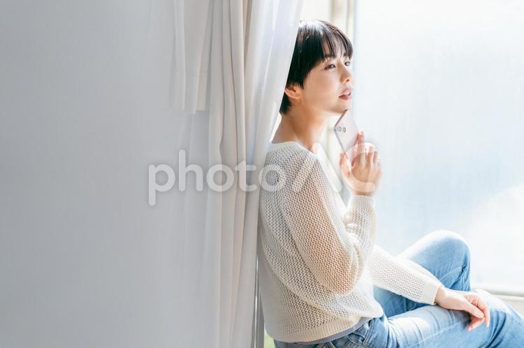 部屋でスマホを操作する女性 スマホ,女性,笑顔の写真素材