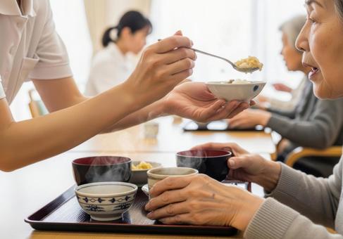 女性介護士が高齢女性に食事介助する場面 女性介護士が高齢女性に食事介助する場面の写真