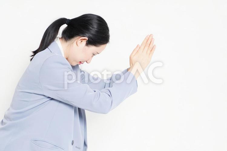 白バックの前に立って、お願いのジェスチャーをする女性 お願い,祈る,頼むの写真素材