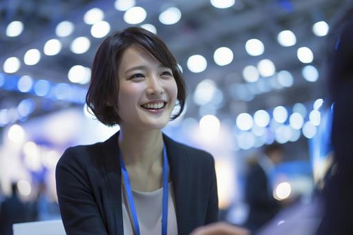 イベント会場で談笑するスーツの女性 イベント会場で談笑するスーツの女性の写真