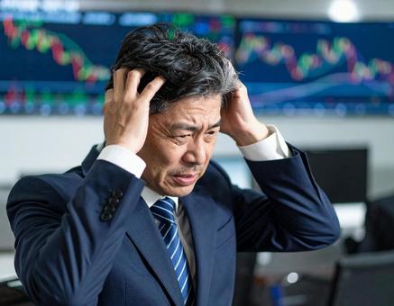 株価暴落にショックを受ける中年男性 株価暴落にショックを受ける中年男性の写真