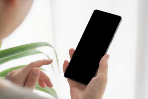明るい部屋でスマホを持っている女性の手元 明るい部屋でスマホを持っている女性の手元の写真
