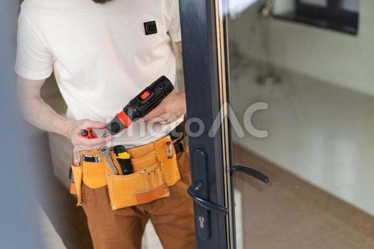 ドアの近くで電動工具を持っている人の手元 窓,ドア,電動工具の写真素材